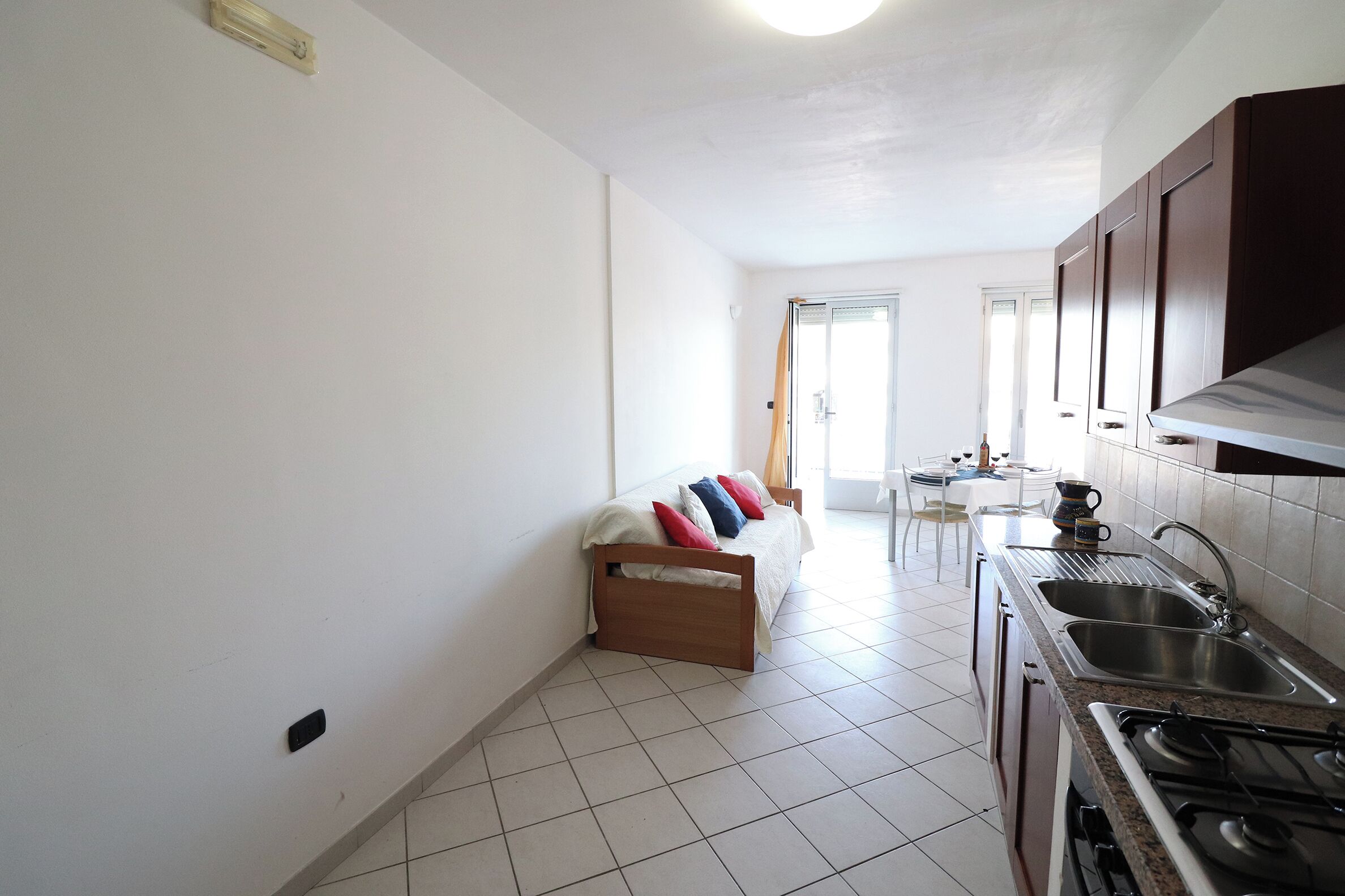 Eine Küche mit Herd, Spüle und Schränken, sowie ein Schlafzimmer mit Bett und Fenster.