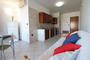 A compact living space with a kitchenette, a dining area, and a sofa with patterned cushions. - Casa Vanessa Modern One-bedroom Apartment With sea View in Central Otranto (Otranto)
