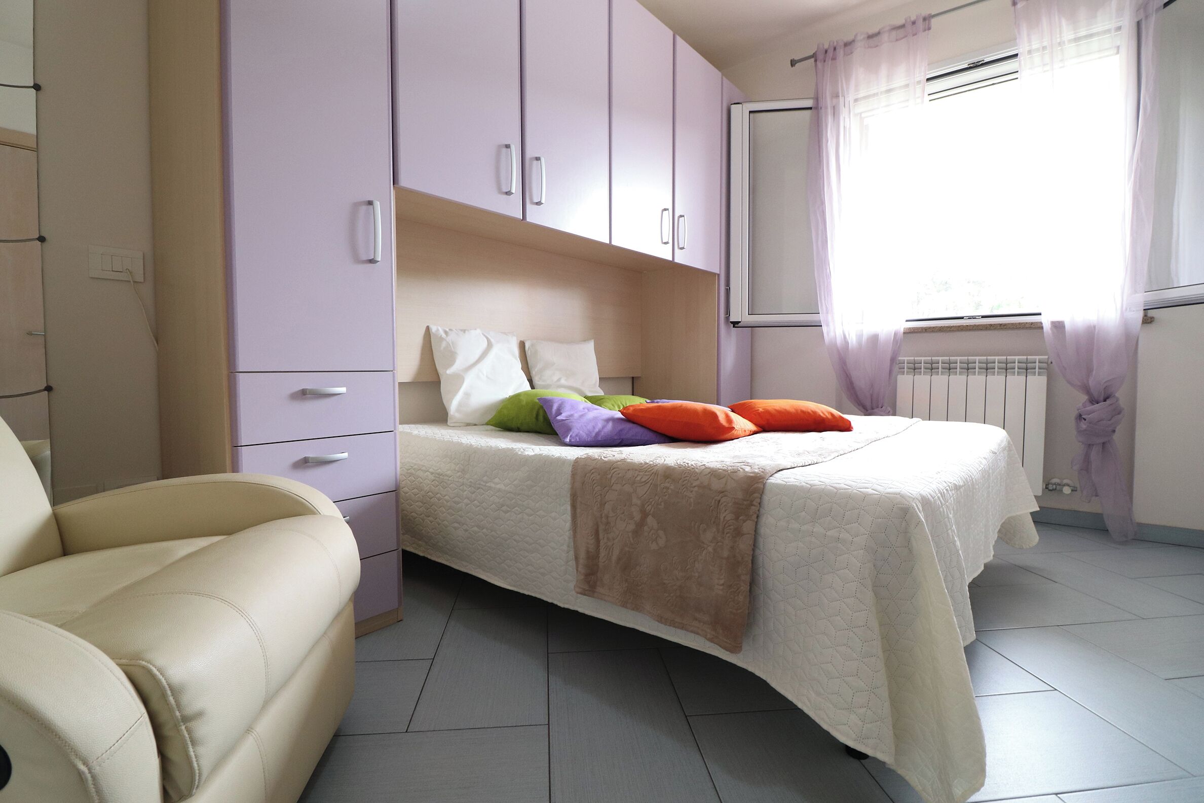 Een slaapkamer met een bed, een stoel en een kledingkast.