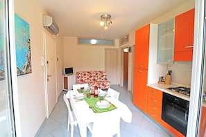 A compact kitchen with a dining area, a built-in oven, and a small seating area with a sofa.