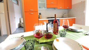 A kitchen with orange cabinets, a dining table set with plates, glasses, and cutlery. - Holiday's Home Claudia 6 People (Otranto)