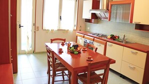 A kitchen with a dining table, chairs, a stove, and a sink. - Holiday Apartment Karm Otranto 6 Places (Otranto)