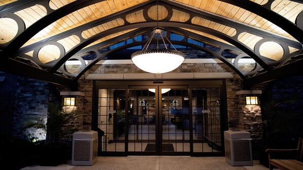 A hotel entrance with a wooden ceiling, a large chandelier, and stone walls.