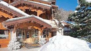 Un edificio de madera con techo nevado y entrada de vidrio.