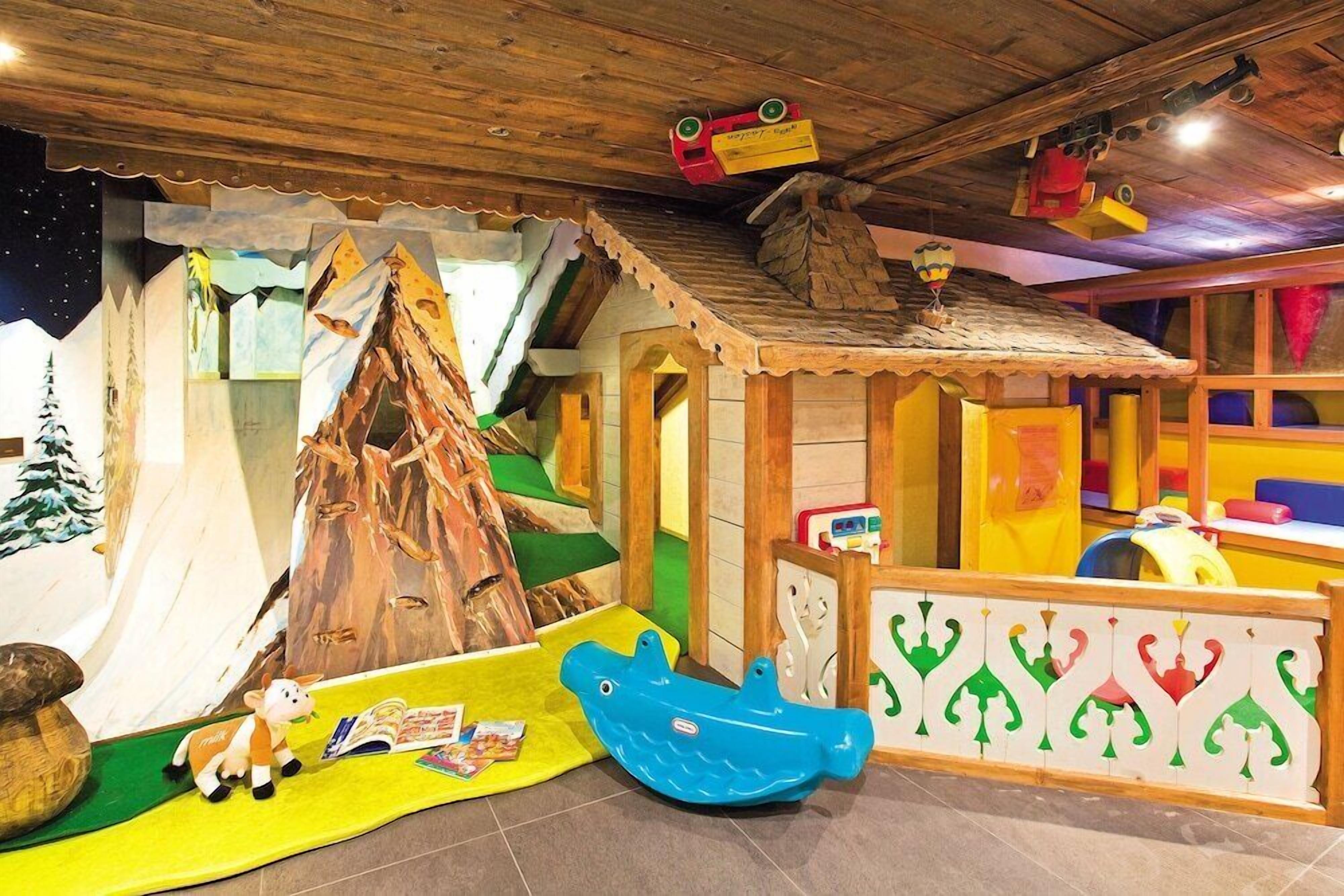 A children's play area with a wooden playhouse, a slide, and various toys.