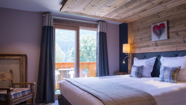 Un dormitorio con una cama grande, un cabecero de madera, una silla y vistas al exterior.