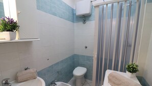 Ein Badezimmer mit Waschbecken, Bidet, Toilette und Dusche. Handtücher liegen auf dem Waschbecken und der Toilette.