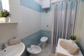 A bathroom with a sink, bidet, toilet, and shower.