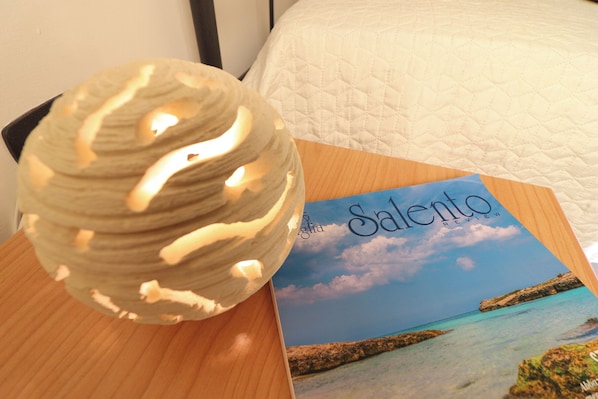 A round, textured object on a wooden surface next to a booklet titled 'Salento Review' with a coastal image.
