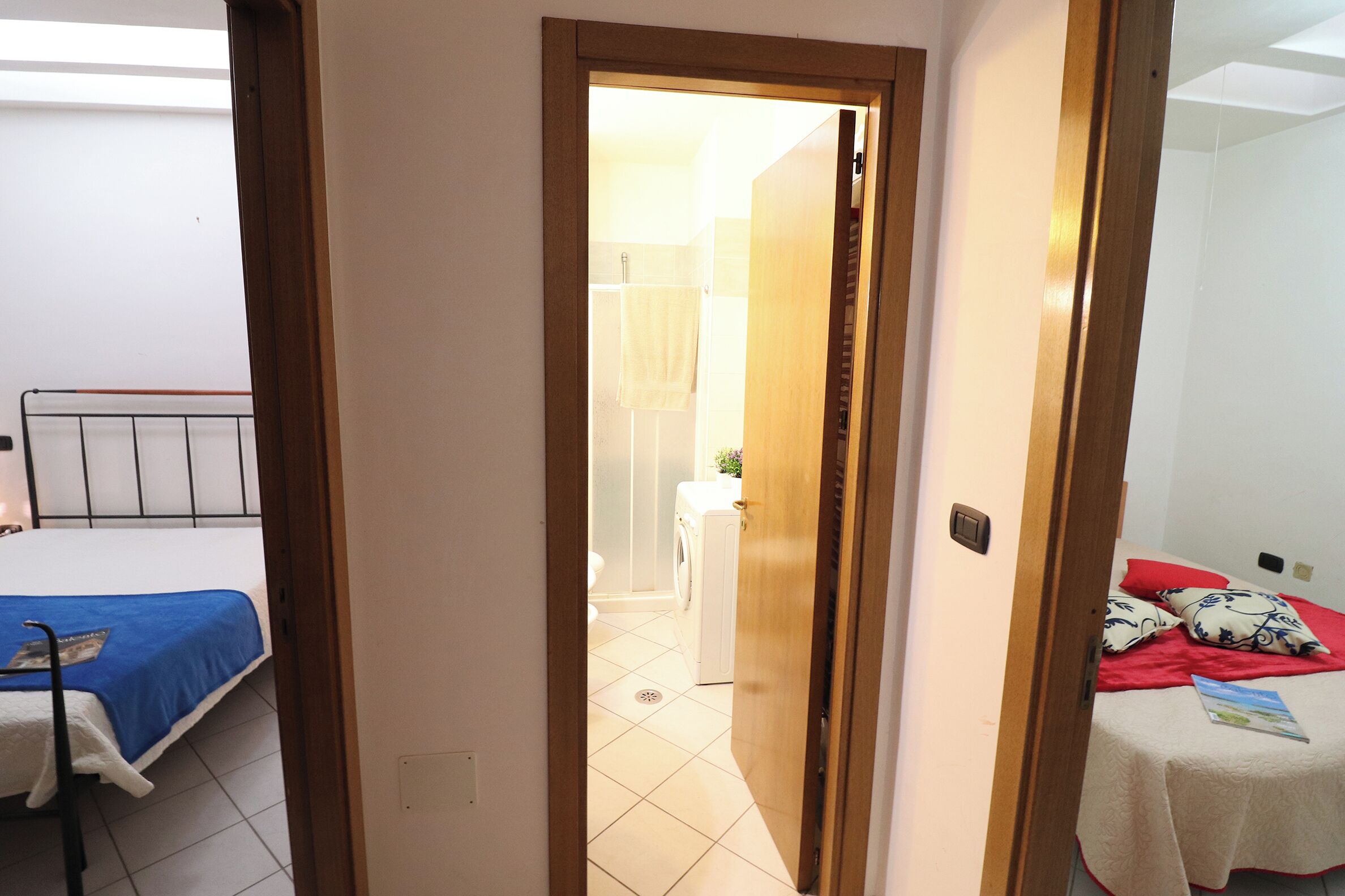 A bedroom with a bed, a wooden door, and a view into another room with a washing machine.