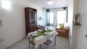 A dining area with a table set for four, a wooden cabinet, and a bed in the background. - Holiday Home "arianna" Elegance and Comfort in the Heart of Otranto (Otranto)