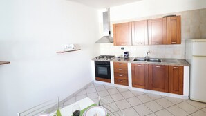 A kitchen with wooden cabinets, a stove, oven, and a refrigerator. - Holiday Home "arianna" Elegance and Comfort in the Heart of Otranto (Otranto)