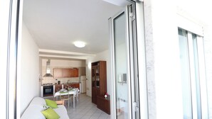 A compact living space with a kitchenette, a dining area, and a bed with green pillows. - Holiday Home "arianna" Elegance and Comfort in the Heart of Otranto (Otranto)