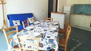A dining area with a table set for four, surrounded by wooden chairs. A blue sofa with patterned cushions is against the wall. - Casa Vacanze "afrodite" Centro Storico Otranto, Salento 6 Posti (Otranto)