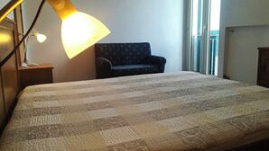 A bedroom with a bed, a desk lamp, a chair, and a window. - Casa Vacanze "afrodite" Centro Storico Otranto, Salento 6 Posti (Otranto)