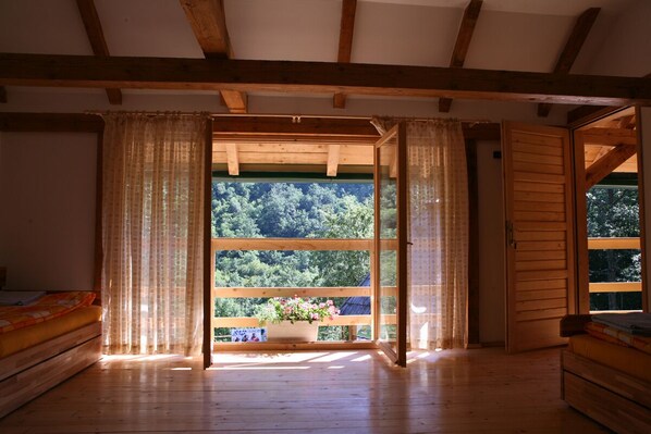 Una habitación de madera con un ventanal grande, vigas de madera y una cama.