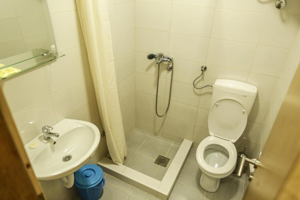 A small bathroom with a sink, toilet, and shower.