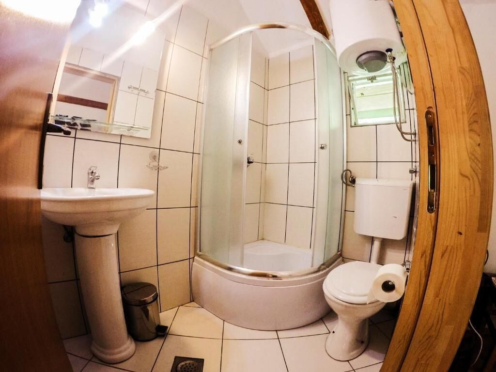 A bathroom with a pedestal sink, toilet, and a glass-enclosed shower.