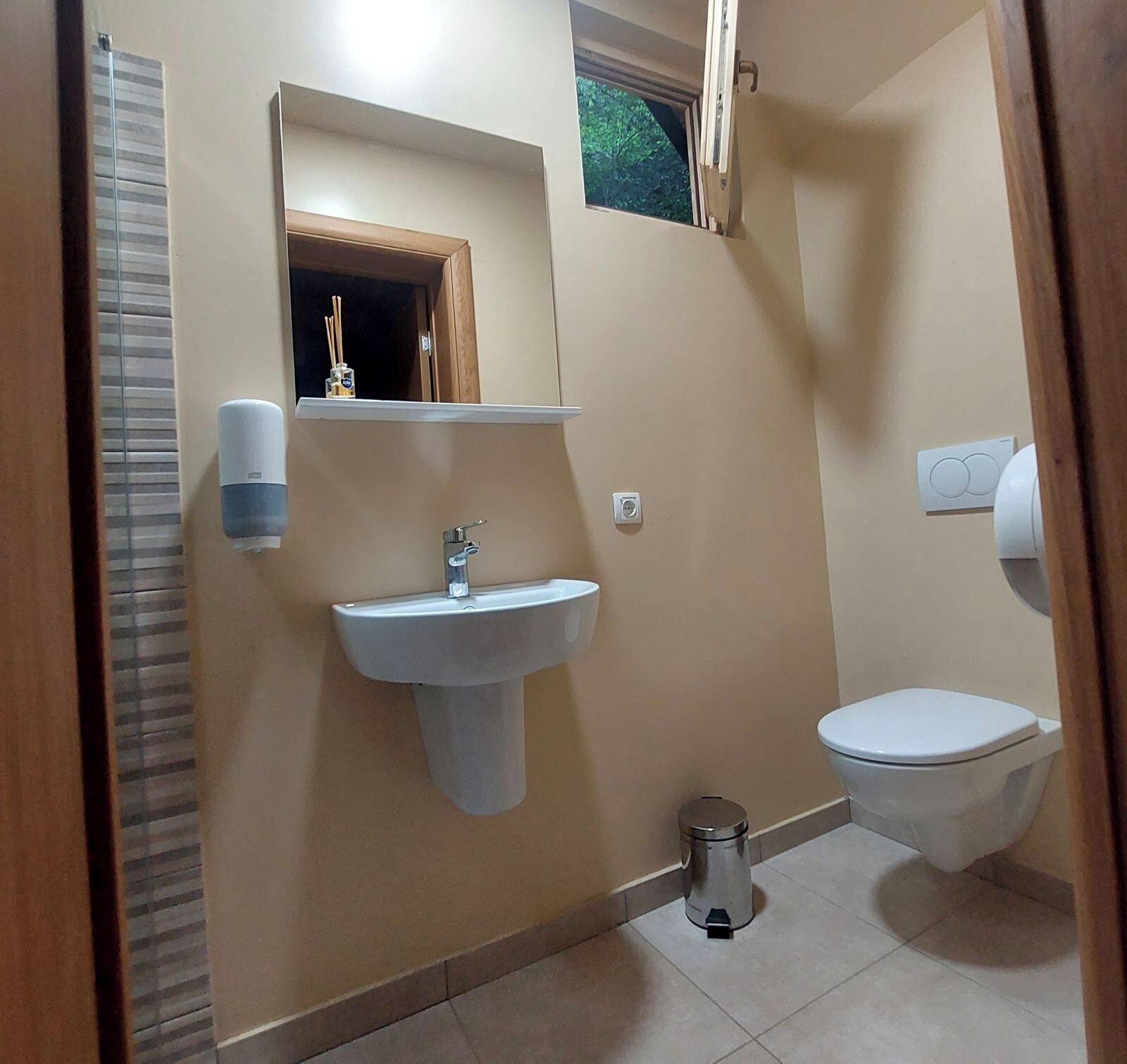 A bathroom with a sink, toilet, and a trash bin.
