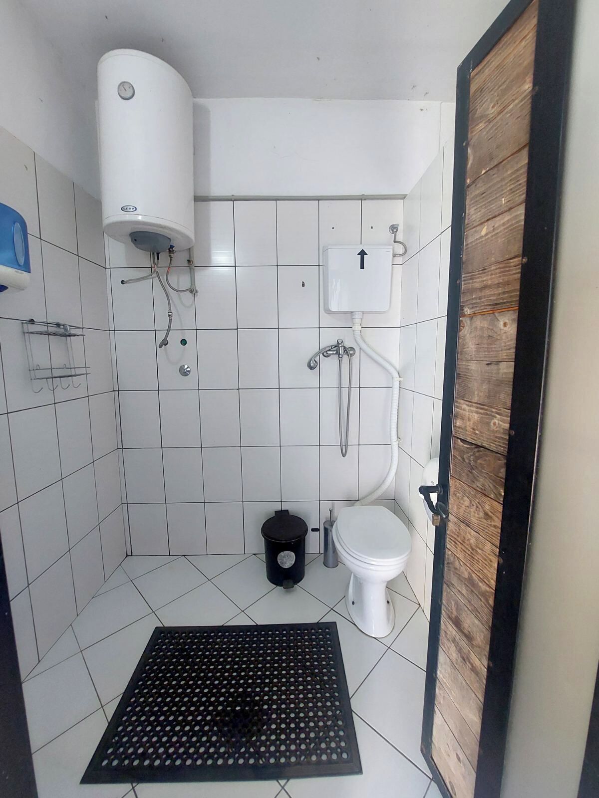 A small, tiled bathroom with a toilet, a shower, and a sink.