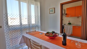 Un comedor con una mesa dispuesta para dos personas, un frutero, una botella de vino y un par de copas.