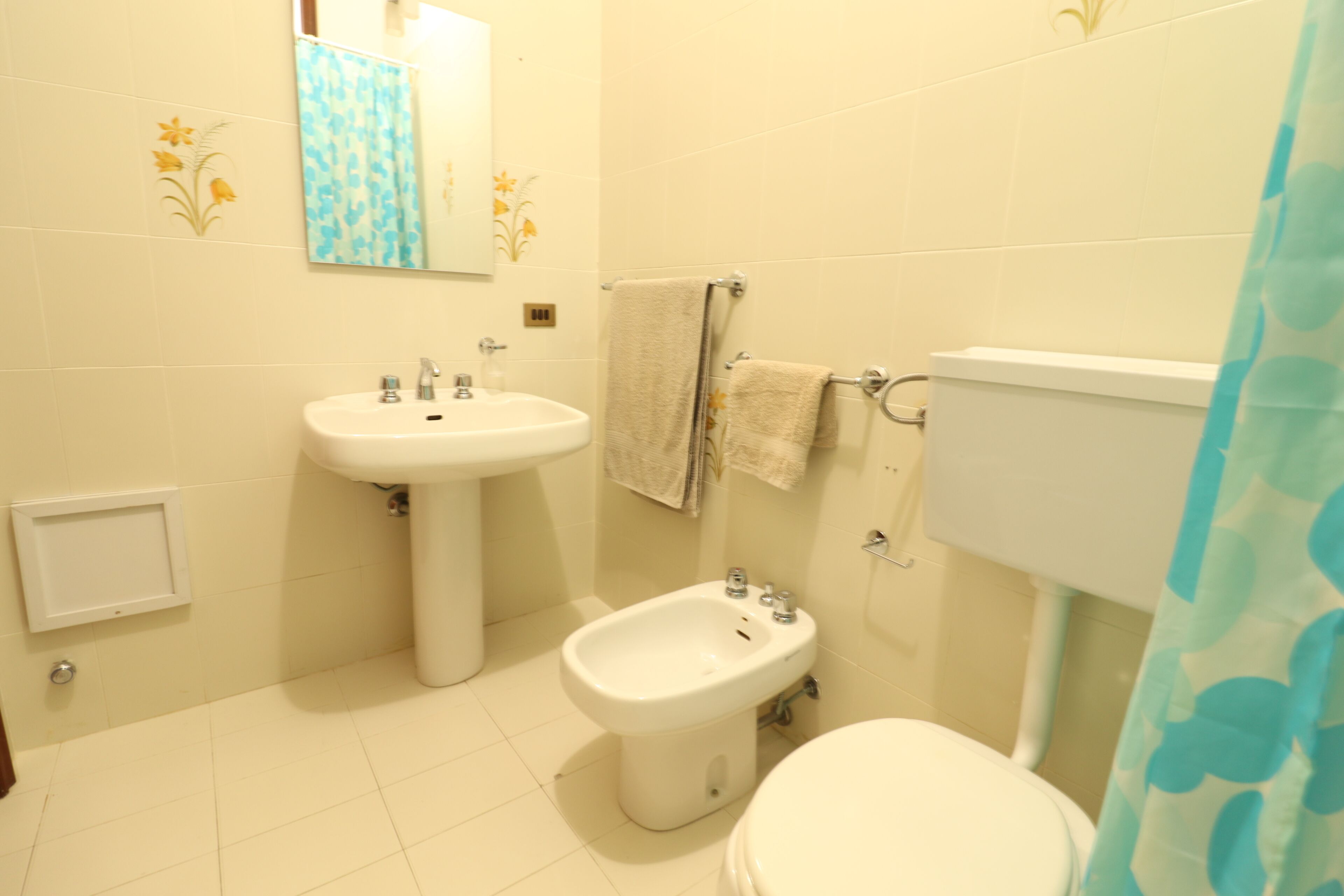 A bathroom with a sink, bidet, toilet, and a shower curtain.