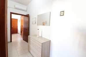 A hallway with a wooden door, a light-colored dresser, and a wall-mounted mirror.