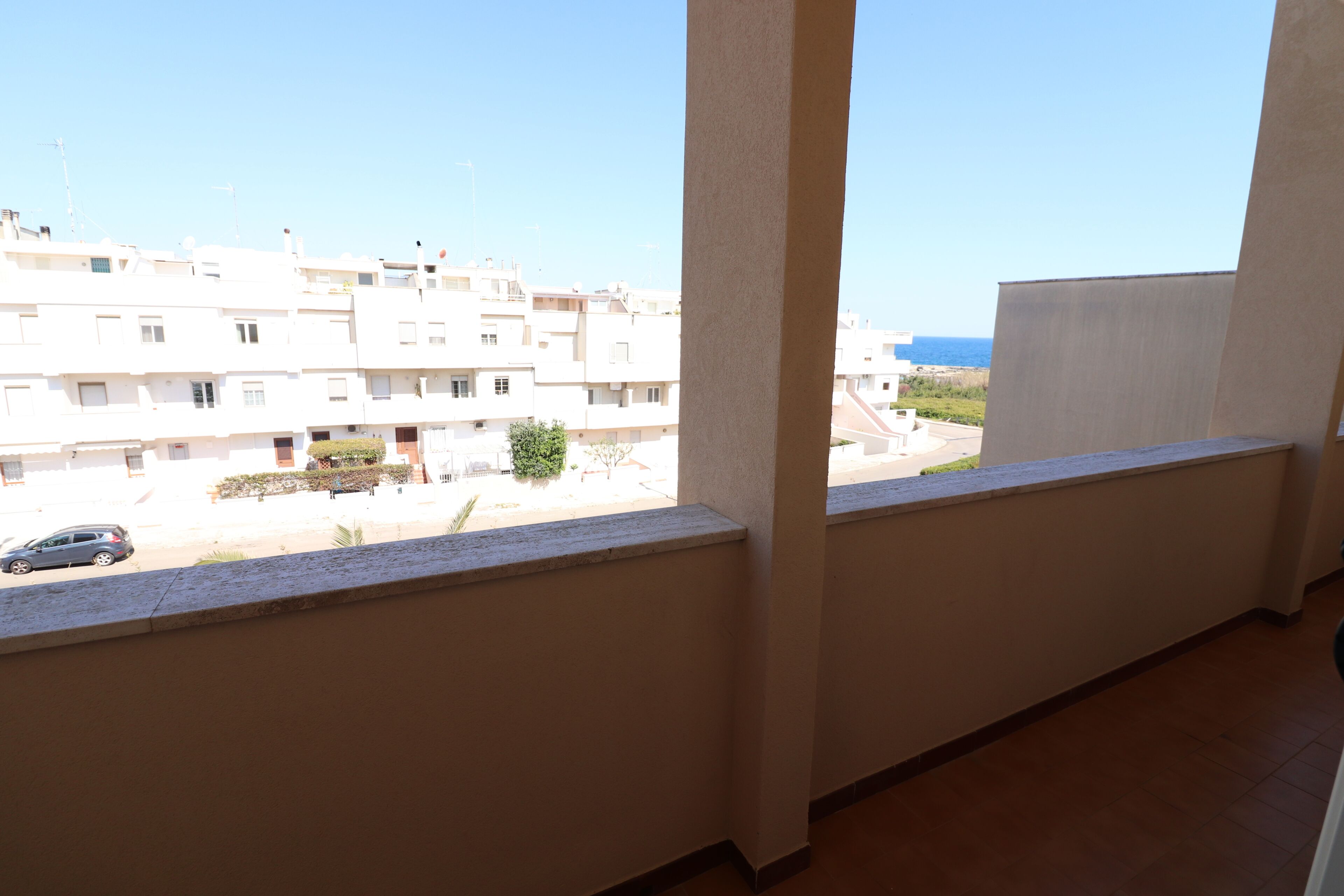 A balcony with a view of a residential area and the sea.