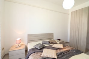 A bedroom with a bed, bedside table, lamp, and wardrobe.