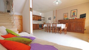 A bedroom with a bed, colorful pillows, a staircase, a dining area with chairs and a table, and a kitchen in the background. - Casa Vacanze Rita 1 Comfort and Space Just Steps From the Sea in Beautiful Otr (Otranto)
