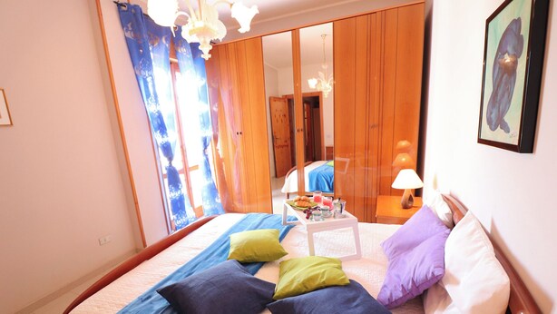 A bedroom with a bed, pillows, a bedside table with a lamp, and a mirror. - Casa Vacanze Rita 1 Comfort and Space Just Steps From the Sea in Beautiful Otr (Otranto)