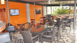 A restaurant with a glass-top table, wicker chairs, and a tiled floor. - Denami Suites (Port Harcourt)