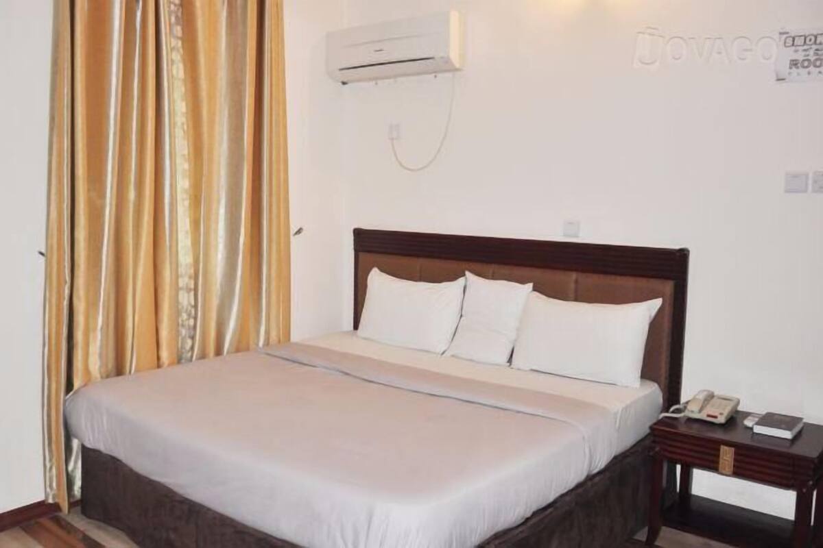 Un dormitorio con cama, mesita de noche, aire acondicionado y puerta.