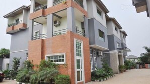 A multi-story residential building with a brick facade, large windows, and balconies. - Denami Suites (Port Harcourt)