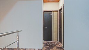 A hallway with a marble-tiled floor, a metal handrail, and a door marked with the number 106. - Punest Hospitality & Hotel (Pune)