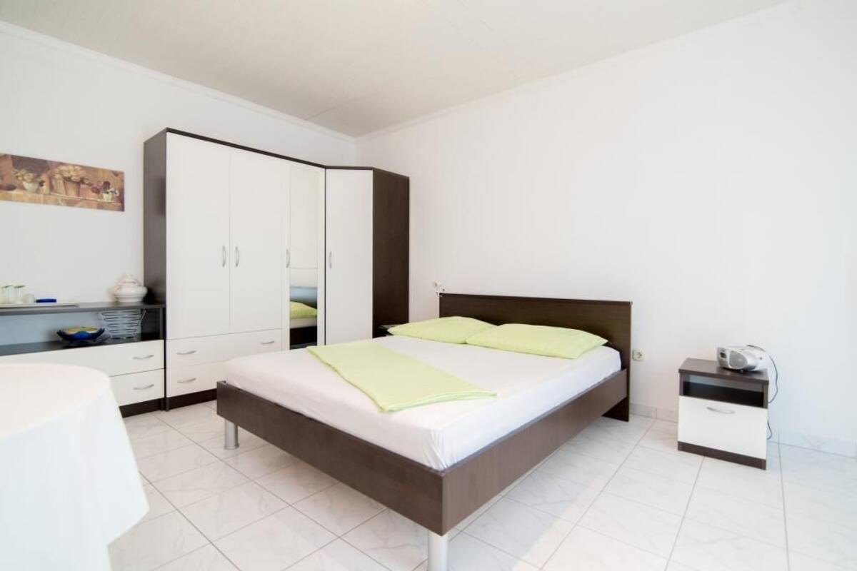 A bedroom with a bed, a wardrobe, a bedside table, and a nightstand.