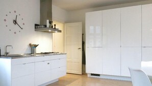 Une cuisine moderne avec des meubles blancs, une cuisinière encastrée et une horloge murale.