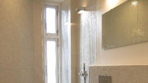 Une salle de bain avec des toilettes, un lavabo, une douche et une fenêtre.