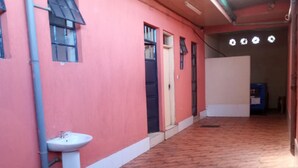 A corridor with a tiled floor, a sink, and a door leading to another room.