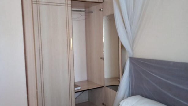 A bedroom with a bed, a wardrobe, and a mirror.