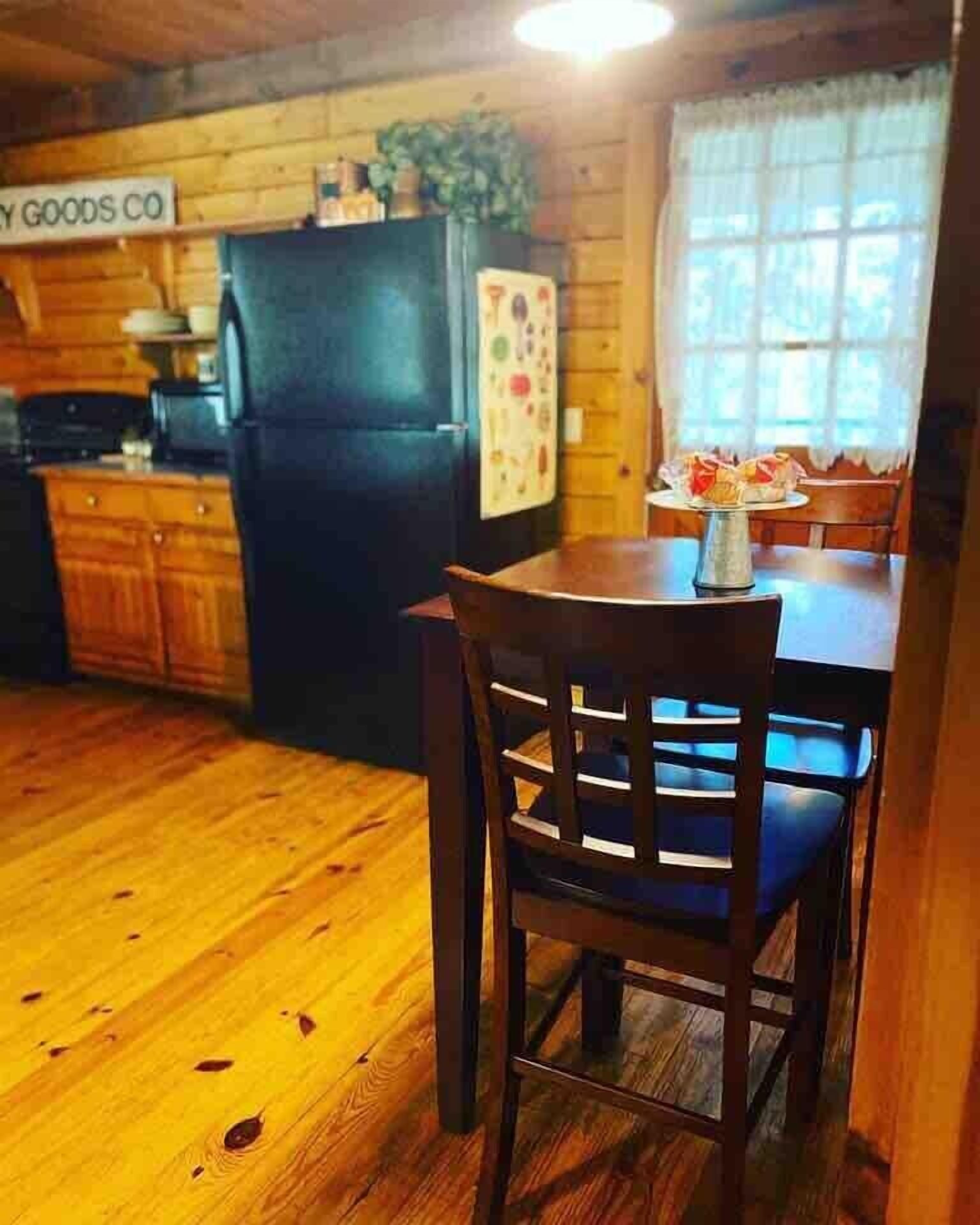 A wooden interior with a dining table and chairs, a refrigerator, and a sign reading "Grocery Co."