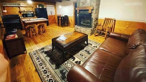 Una sala de estar acogedora con chimenea de piedra, sofá de cuero y una zona de comedor con mesa y sillas de madera.