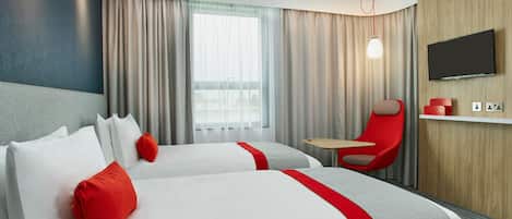 Quarto de hotel com duas camas, uma televisão, uma cadeira vermelha e uma mesa pequena.