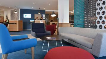 A modern lobby with a reception desk, seating area, and a decorative wall.