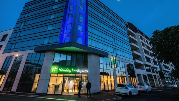 Um hotel Holiday Inn Express com fachada de vidro moderna e sinalização iluminada.