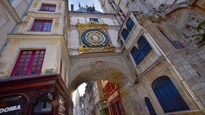 Um edifício histórico com uma torre de relógio imponente, detalhes arquitetônicos elaborados e uma passagem estreita.
