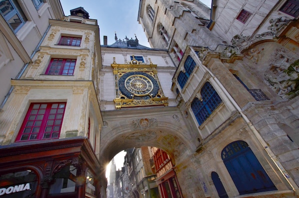 Un edificio histórico con una imponente torre de reloj, detalles arquitectónicos ornamentales y un estrecho pasaje.