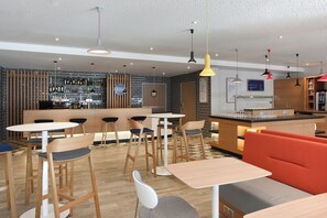 A modern bar area with a counter, stools, and a variety of bottles and glasses. - Holiday Inn Express Rouen Centre-rive Gauche (Rouen)