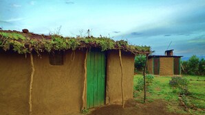 A rustic house with a green door and a thatched roof. - Olonyori Maasai House (Maasai Mara)