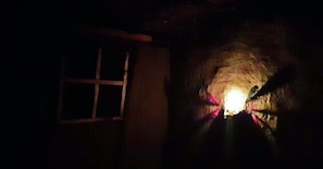 A dimly lit room with a single window and a light source in the center. - Olonyori Maasai House (Maasai Mara)